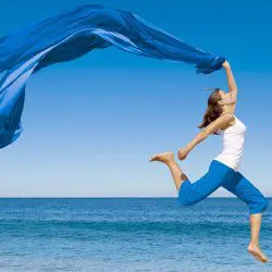 image of woman jumping for joy on the beach