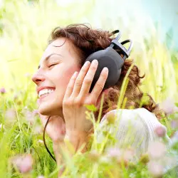 image of woman blissfully happy lying in the grass listening to music