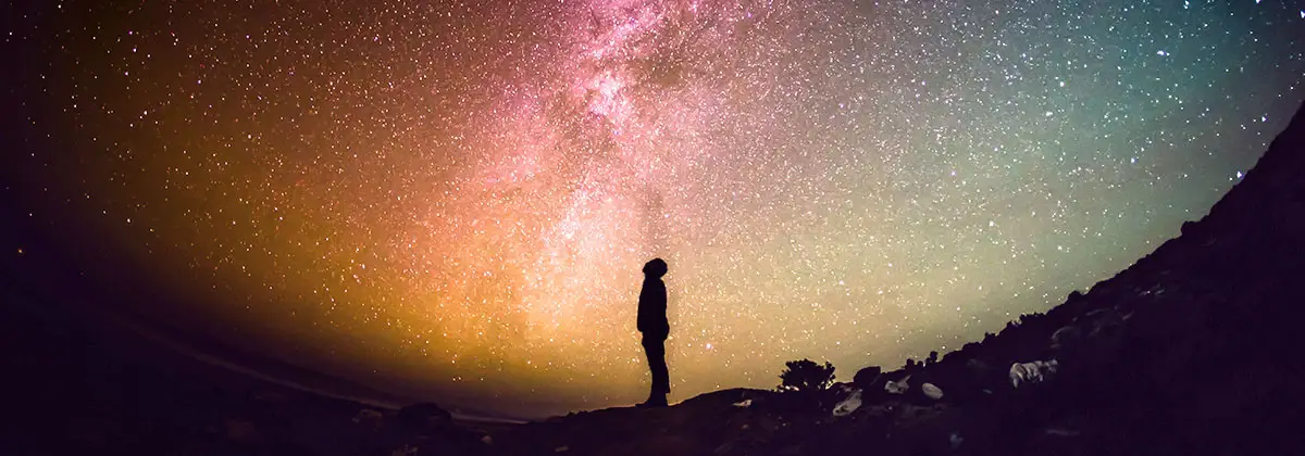 person silhouetted against the evening sky of stars