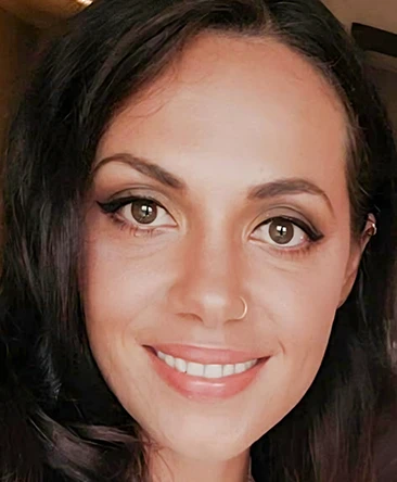 Portrait of Aimee, an intuitive psychic reader and tarot specialist, smiling warmly, with dark hair and natural makeup, offering compassionate phone psychic readings and spiritual guidance.