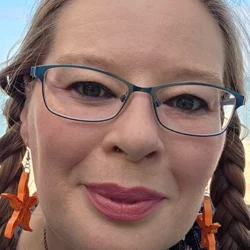 Psychic Christina smiling outdoors wearing glasses and star earrings
